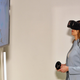Meta abandonne le casque VR Quest d'origine 1 Une femme portant un casque Oculus Quest VR tenant des contrôleurs et regardant un écran.